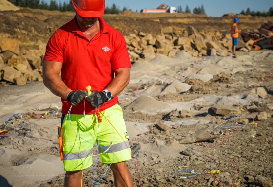 Na fotografii střelmistr, pan Ing. Jan Donocik, Ph.D., dokončuje propojení rozbušek těsně před clonovým odstřelem.